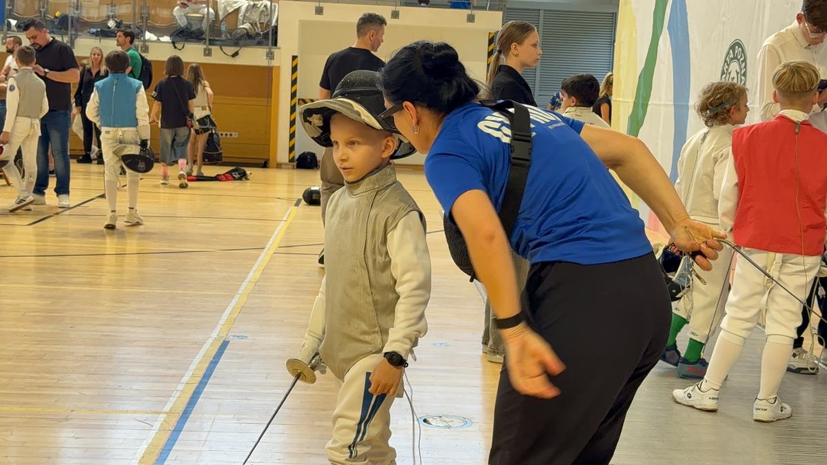 Coach talking to a young fencer at a tournament